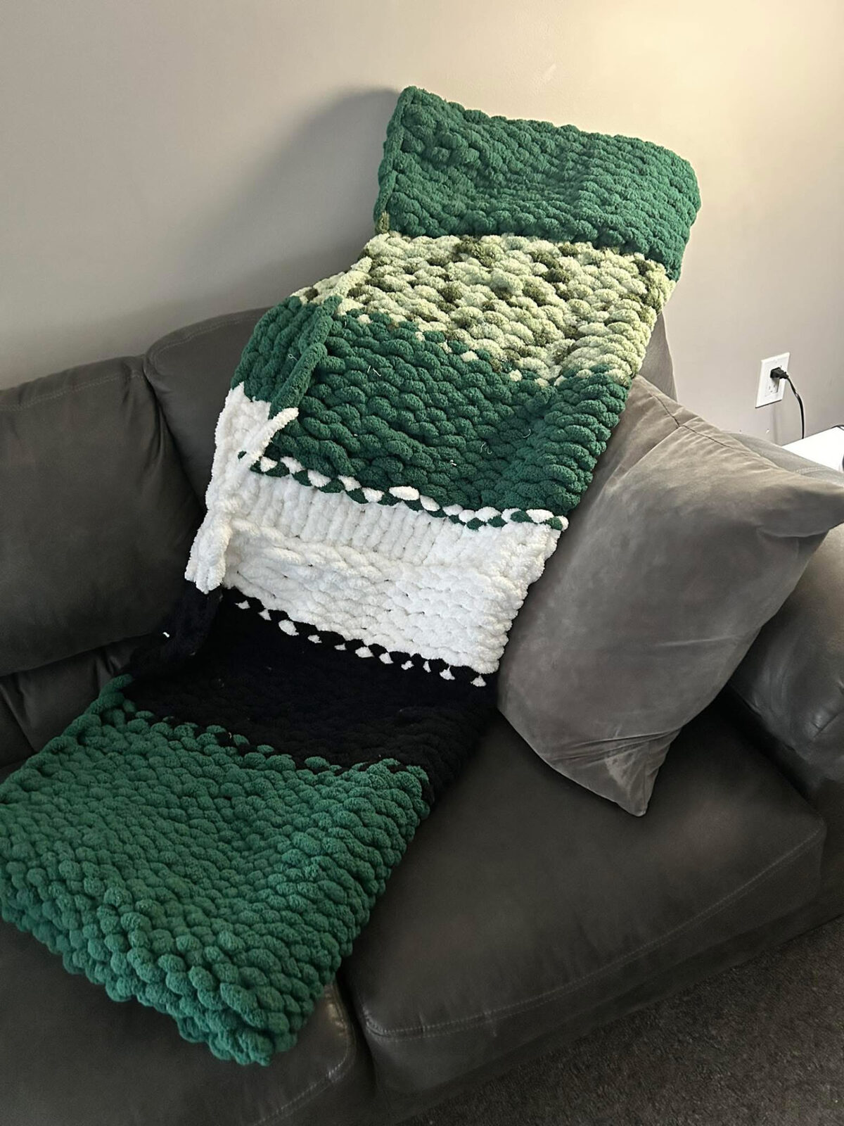 Green, white, and black chunky knit throw on a couch